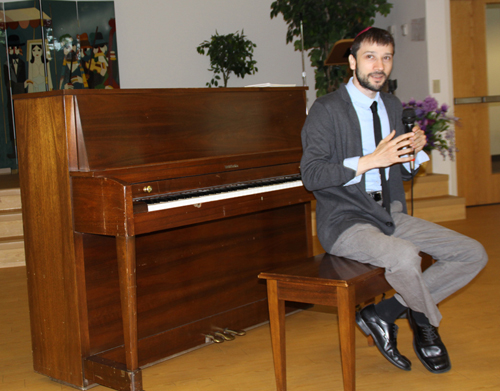 Dan Karlsberg, at the piano, talking to the audience.