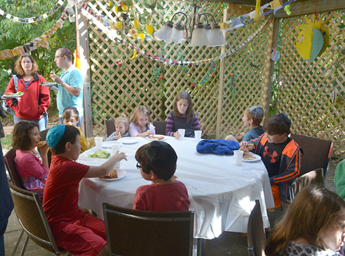 Kids eating at a table in the Sukkah